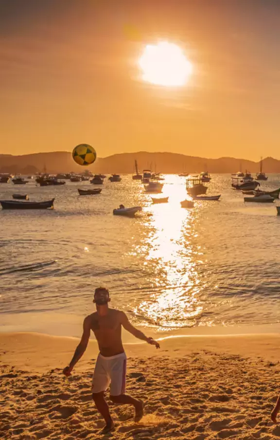 Imagem de uma pessoa jogando futebol na praia de Búzios, capturando o espírito esportivo e descontraído da cidade. Perfeito para quem busca atividades ao ar livre em seu pacote de viagem.