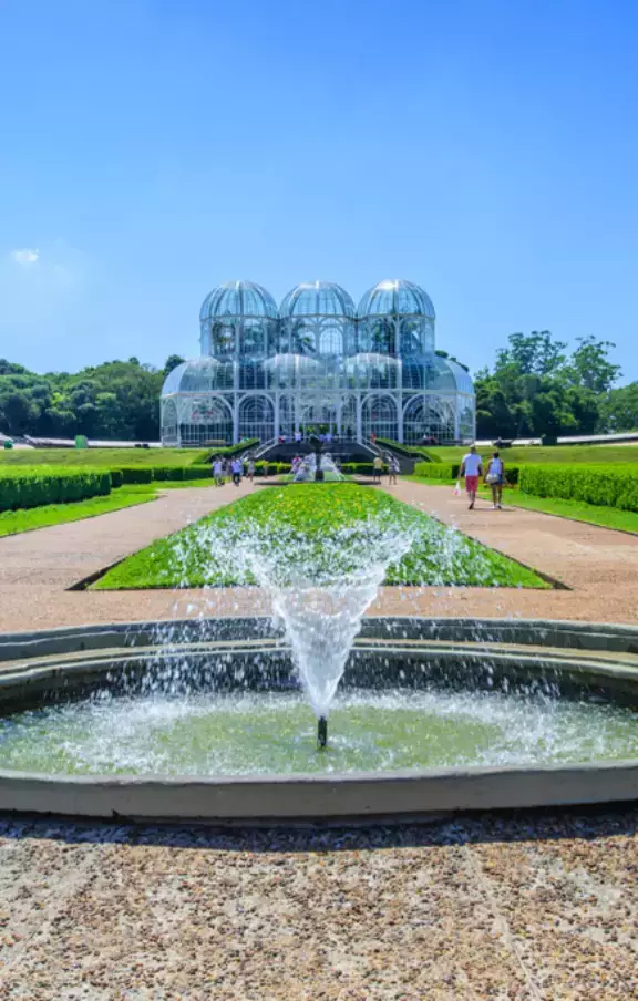 Imagem do icônico Jardim Botânico de Curitiba, destacando a estufa de vidro e a variedade de flora. Um oásis de tranquilidade e beleza no coração da cidade