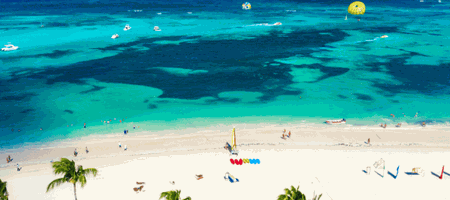 Tenda de palha em frente ao mar de cor incrível em um dia ensolarado em Punta Cana. Areia muito clara se confunde com as nuvens ao fundo.