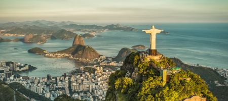 Linda paisagem de final de tarde do Cristo Redentor em vista panorâmica, ao fundo a cidade do Rio de Janeiro com suas belezas naturias e o Pão de Açúcar.