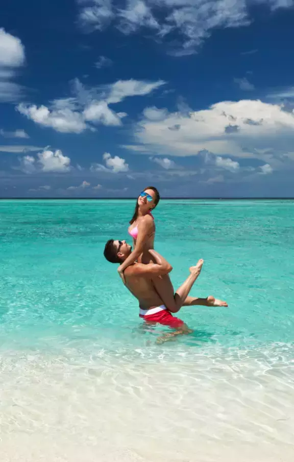 Imagem romântica de um casal se abraçando nas águas cristalinas de Cancún, compartilhando momentos de amor e felicidade. Ideal para quem procura pacotes de viagens românticas.