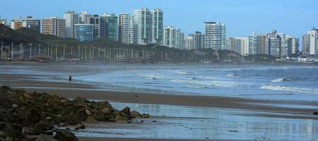 Visão panorâmica da praia de São Luís no fim da tarde com turistas se banhando.