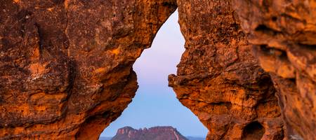 Contemple o magnífico Portal da Chapada das Mesas na imagem, onde a natureza esculpiu uma janela natural oferecendo vistas deslumbrantes do parque nacional brasileiro, ideal para ecoturismo e aventura