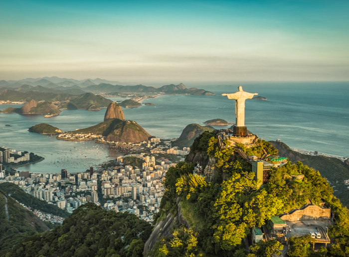 Linda paisagem de final de tarde do Cristo Redentor em vista panorâmica, ao fundo a cidade do Rio de Janeiro com suas belezas naturias e o Pão de Açúcar.