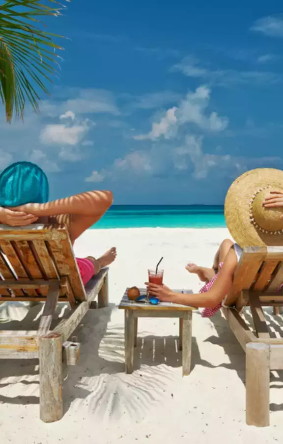 Foto de um casal relaxando em espreguiçadeiras em Cancún, desfrutando do sol e da brisa do mar. Uma cena romântica perfeita para casais em busca de pacotes de viagens amorosas