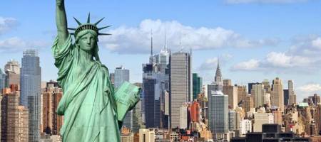 Estátua da liberdade em Nova Iorque, ao fundo a ilha de Manhattan, com edifícios famosos como o Empire State Building.
