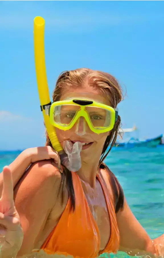 Foto de uma mulher explorando o mundo subaquático de Cancún através do snorkel, descobrindo a rica vida marinha da região. Uma atividade imperdível para os amantes do mar.