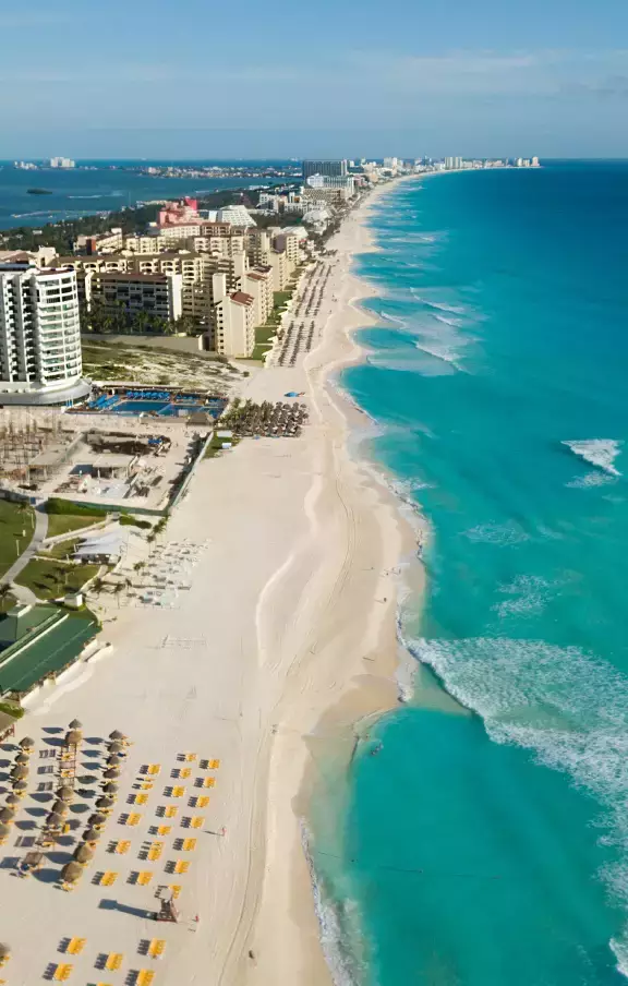 Vista aérea espetacular da costa de Cancún, mostrando a extensão das praias e o contraste das águas claras com o verde da vegetação. Uma perspectiva única para quem busca aventuras em Cancún.