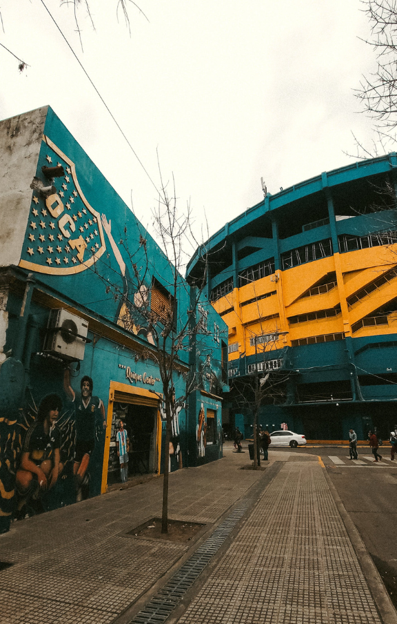 Vista diurna e nublada do icônico Estádio do Boca Juniors em Buenos Aires, Argentina. Cores realçadas para destacar a arquitetura única do estádio. Perfeito para quem busca pacotes de viagens com experiências esportivas